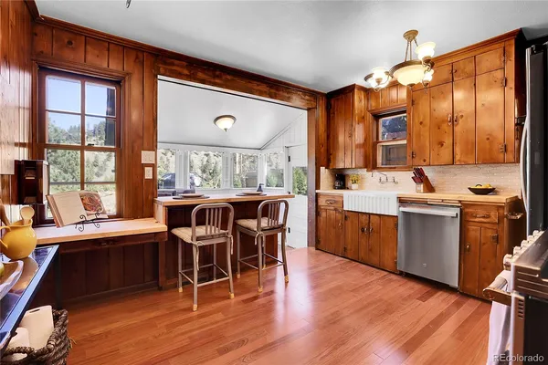 a dining hall with stainless steel appliances granite countertop a stove top oven a dining table and chairs with wooden floor