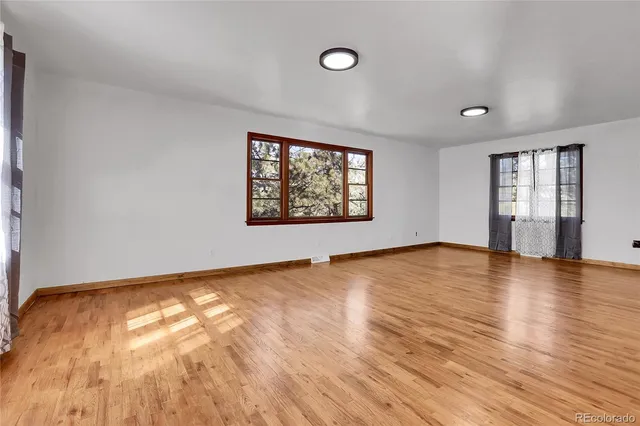 an empty room with wooden floor and windows