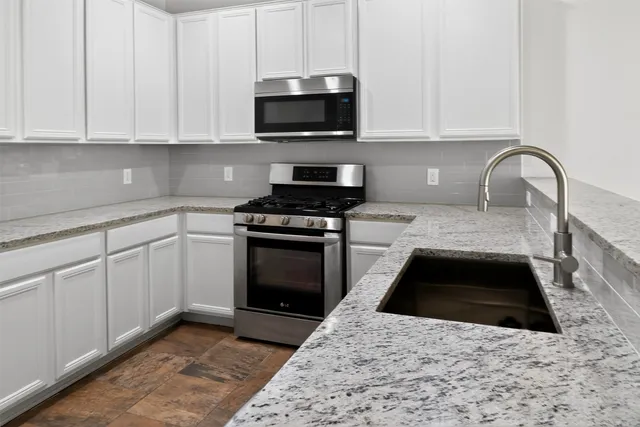 a kitchen with granite countertop stainless steel appliances a stove a sink and a microwave