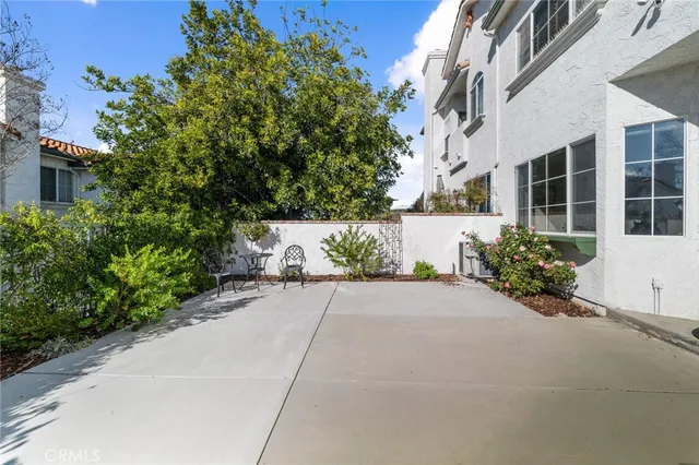 a view of a white house with a yard and table and chairs under an umbrella