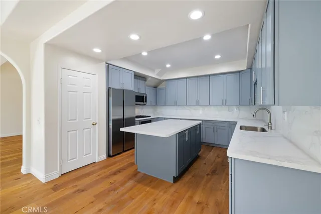 a kitchen with a sink a stove a refrigerator and a oven with wooden floor
