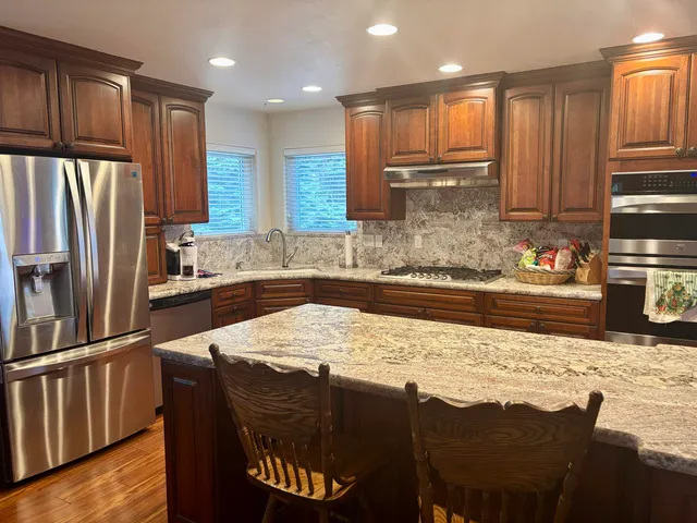 a kitchen with granite countertop a sink cabinets and stainless steel appliances