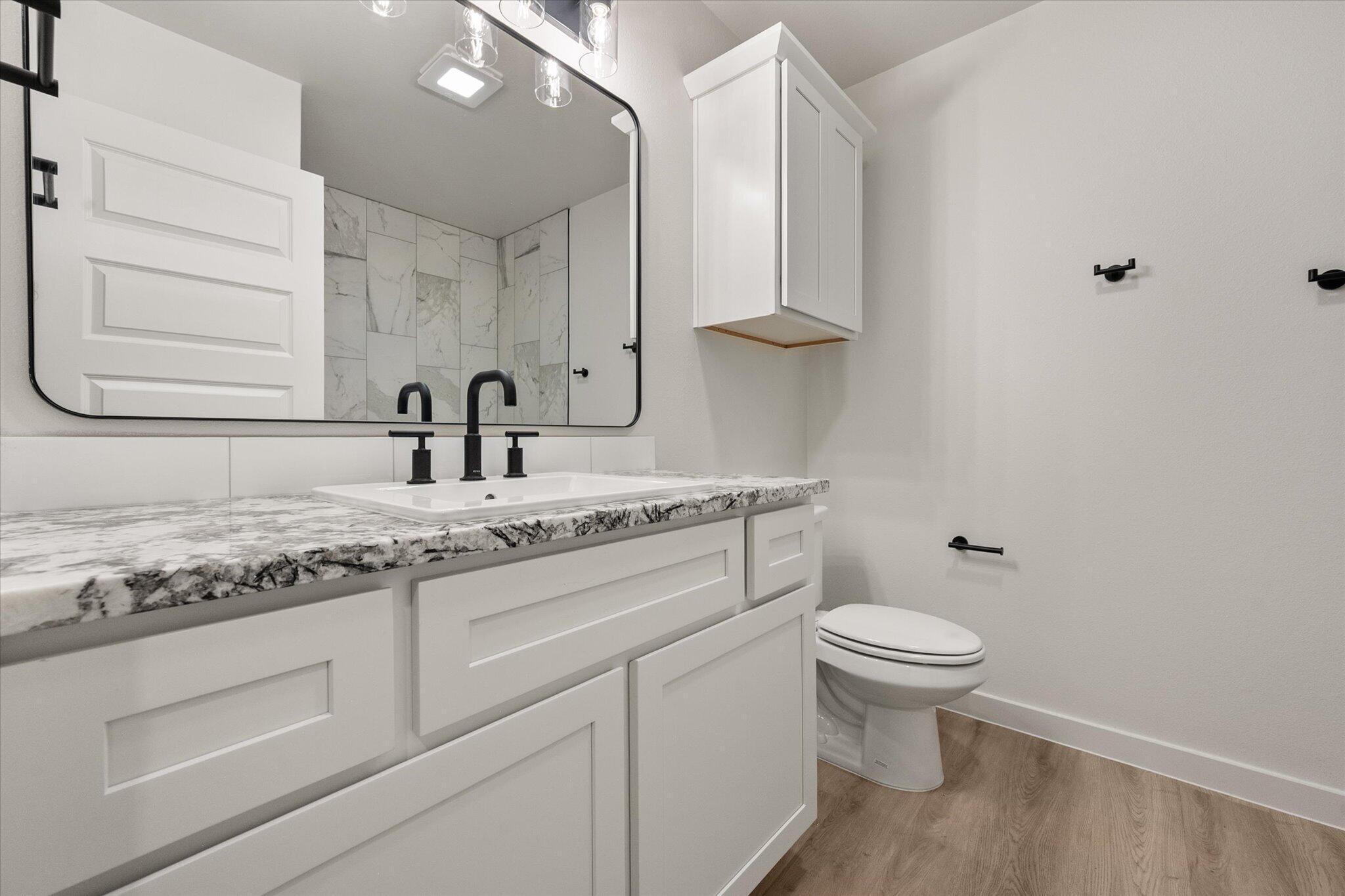 6927 53rd Street Lubbock, TX 79407 - Photo 17 of 21 a bathroom with a granite countertop sink a toilet and a mirror