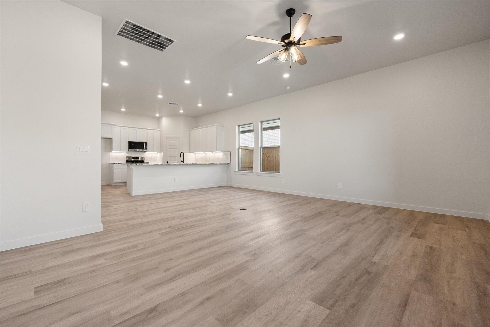 6927 53rd Street Lubbock, TX 79407 - Photo 4 of 21 a view of an empty room and kitchen view with wooden floor