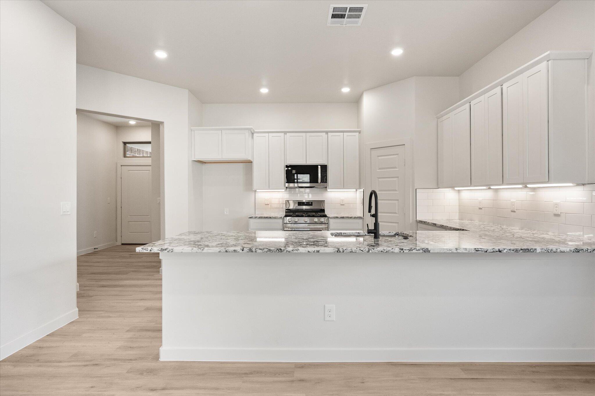 6927 53rd Street Lubbock, TX 79407 - Photo 6 of 21 a large kitchen with granite countertop a large counter top stainless steel appliances and cabinets
