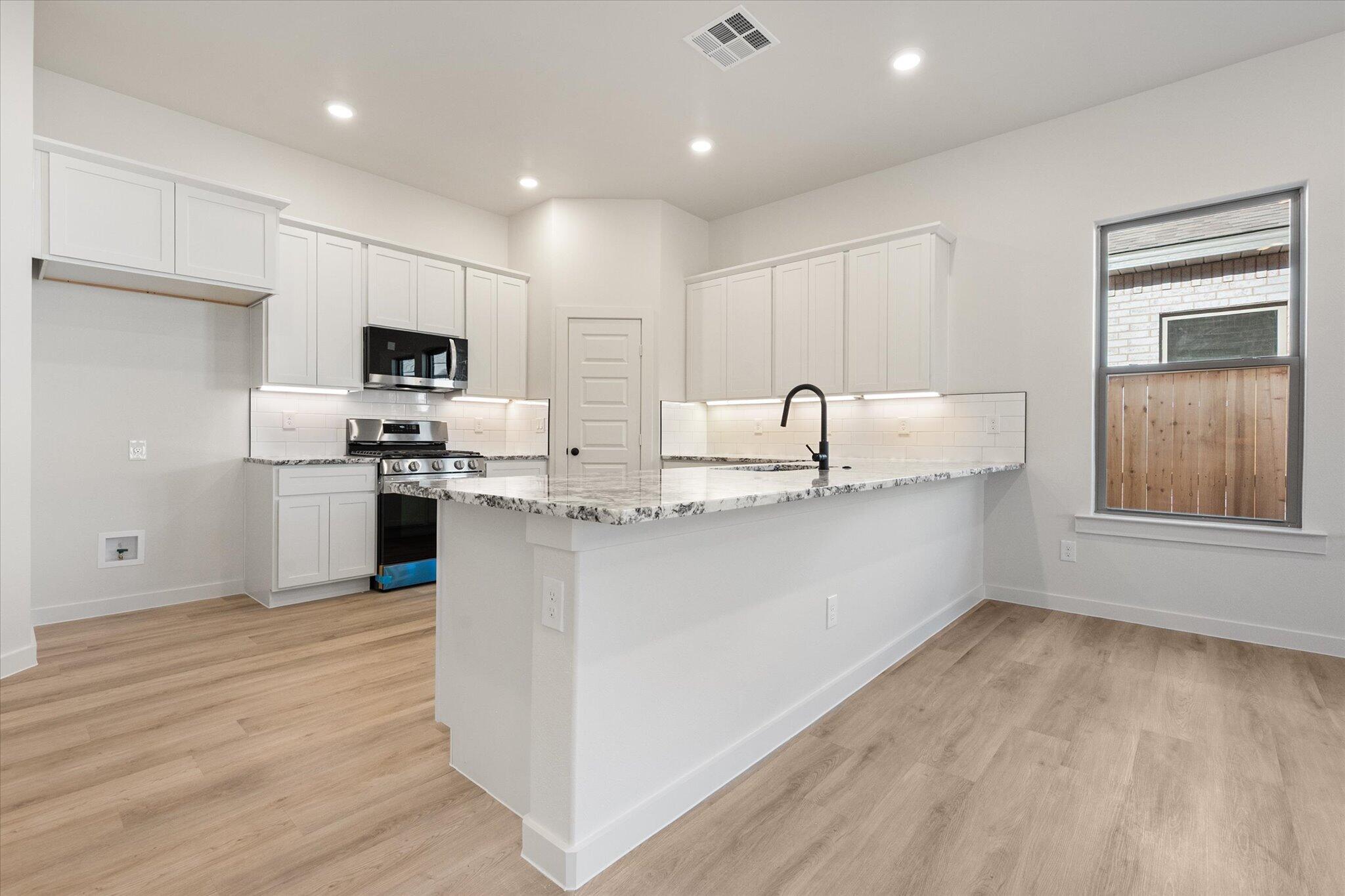 6927 53rd Street Lubbock, TX 79407 - Photo 8 of 21 a kitchen with kitchen island granite countertop a sink cabinets and stainless steel appliances