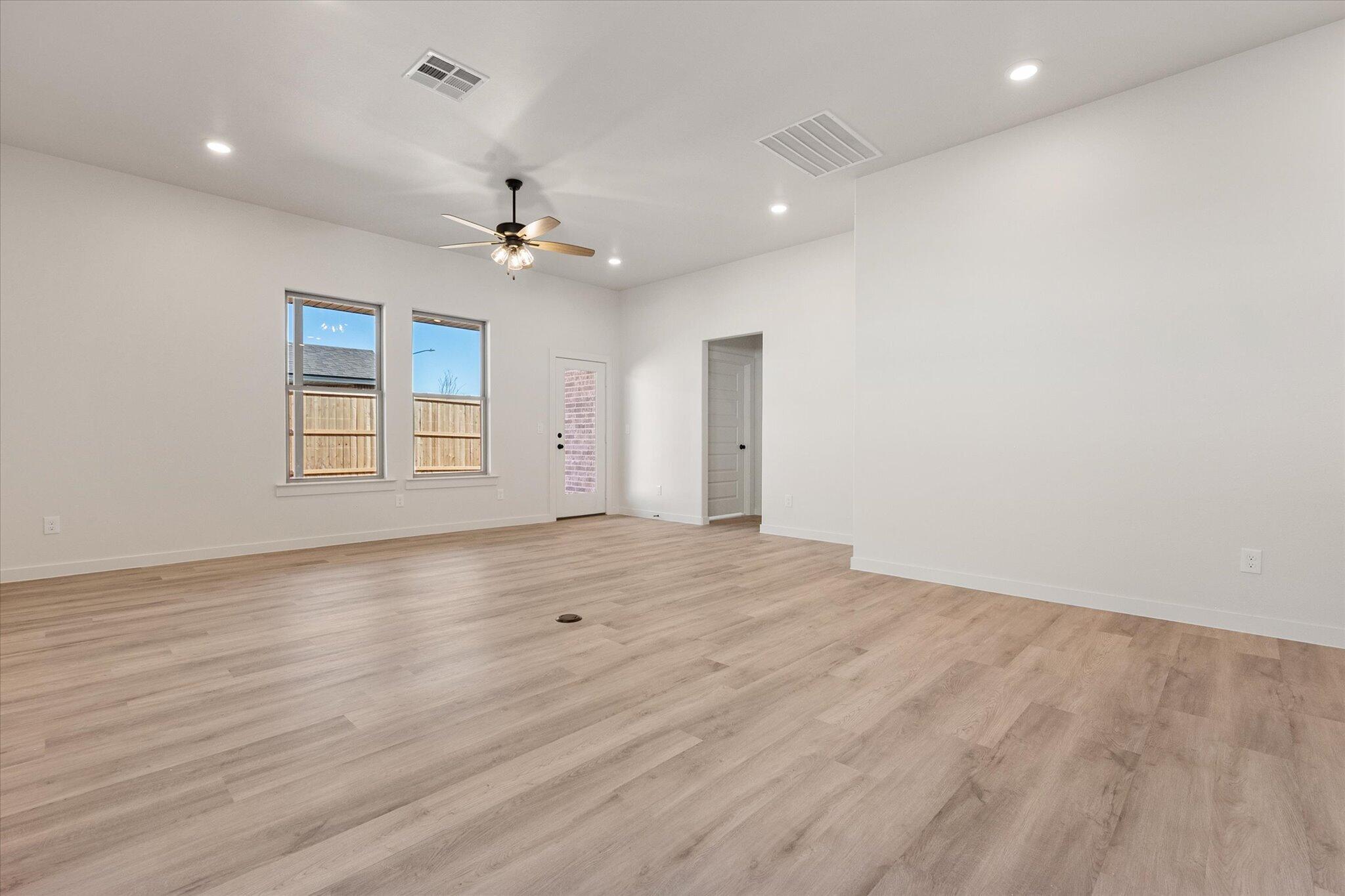 6927 53rd Street Lubbock, TX 79407 - Photo 9 of 21 an empty room with wooden floor ceiling fan and windows