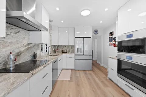 a large kitchen with stainless steel appliances kitchen island granite countertop a stove a sink and a white cabinets