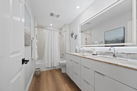 a bathroom with a double vanity sink a mirror a bathtub and shower