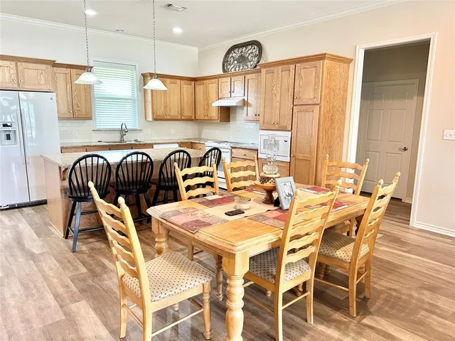 a kitchen with stainless steel appliances kitchen island granite countertop a dining table and chairs