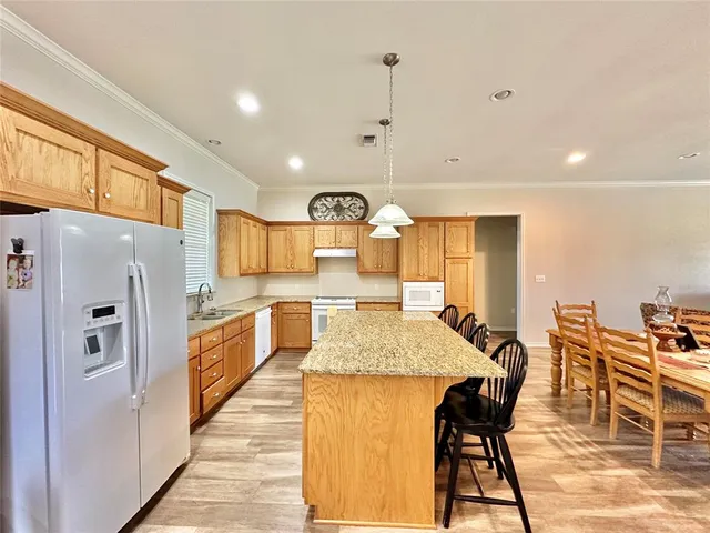 a large kitchen with stainless steel appliances kitchen island granite countertop a table chairs and a refrigerator