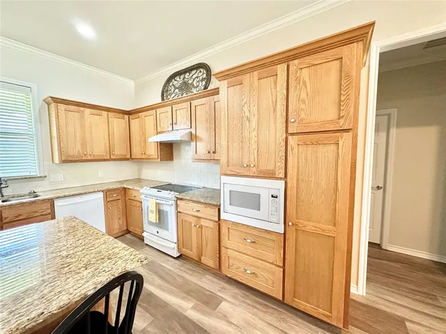 a kitchen with stainless steel appliances granite countertop a stove a sink and a refrigerator with wooden floor