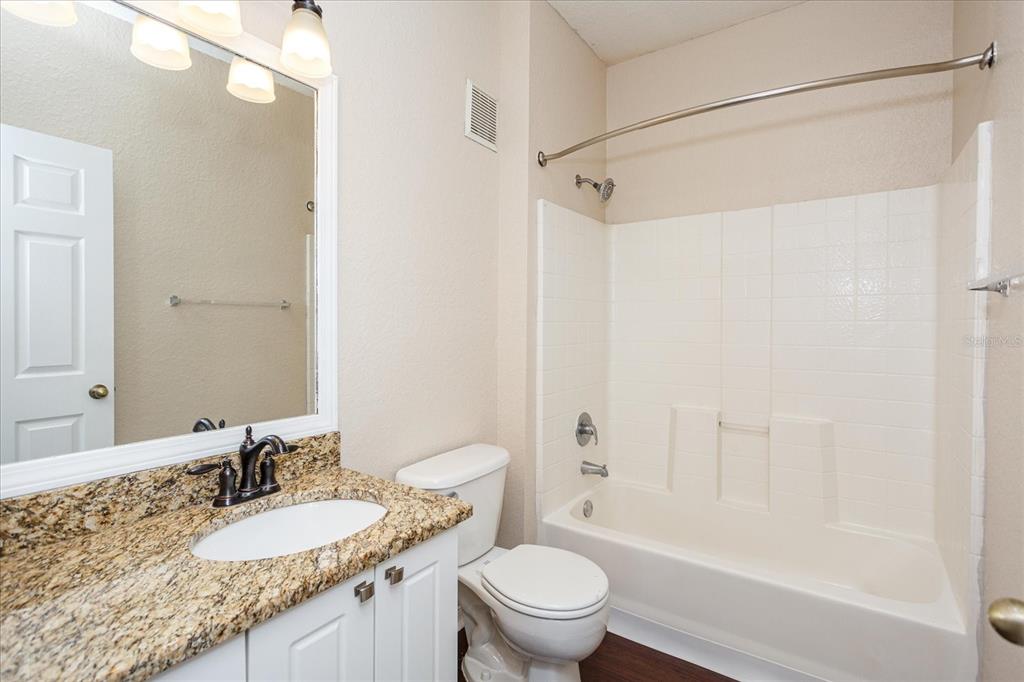 819 Grand Regency Pointe, Unit 203 Altamonte Springs, FL 32714 - Photo 15 of 21 a bathroom with a granite countertop sink a mirror a toilet and bathtub