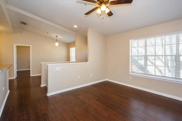 a view of an empty room with wooden floor and a window