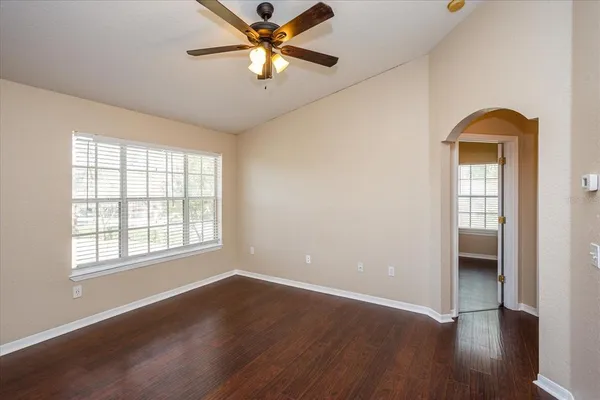 an empty room with wooden floor closet and windows