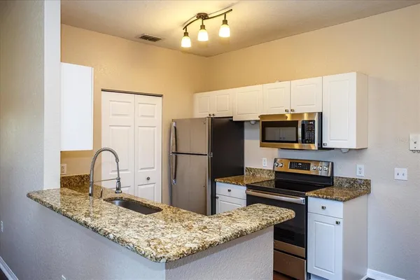 a kitchen with stainless steel appliances granite countertop a sink refrigerator and microwave