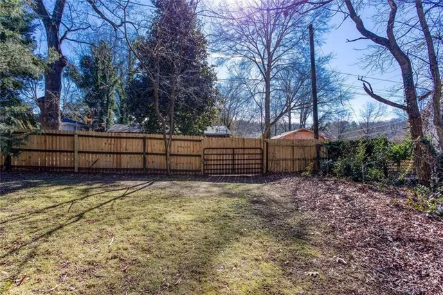 a view of backyard with wooden fence and large trees
