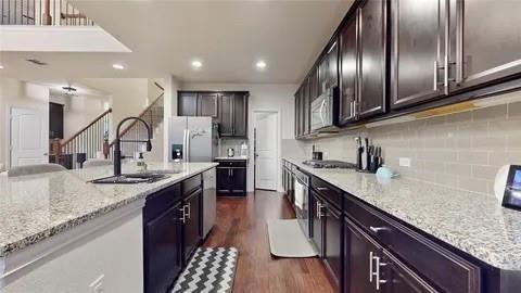 3308 Knoll Pines Road Denton, TX 76208 - Photo 3 of 13 a kitchen with granite countertop stainless steel appliances a sink stove and cabinets