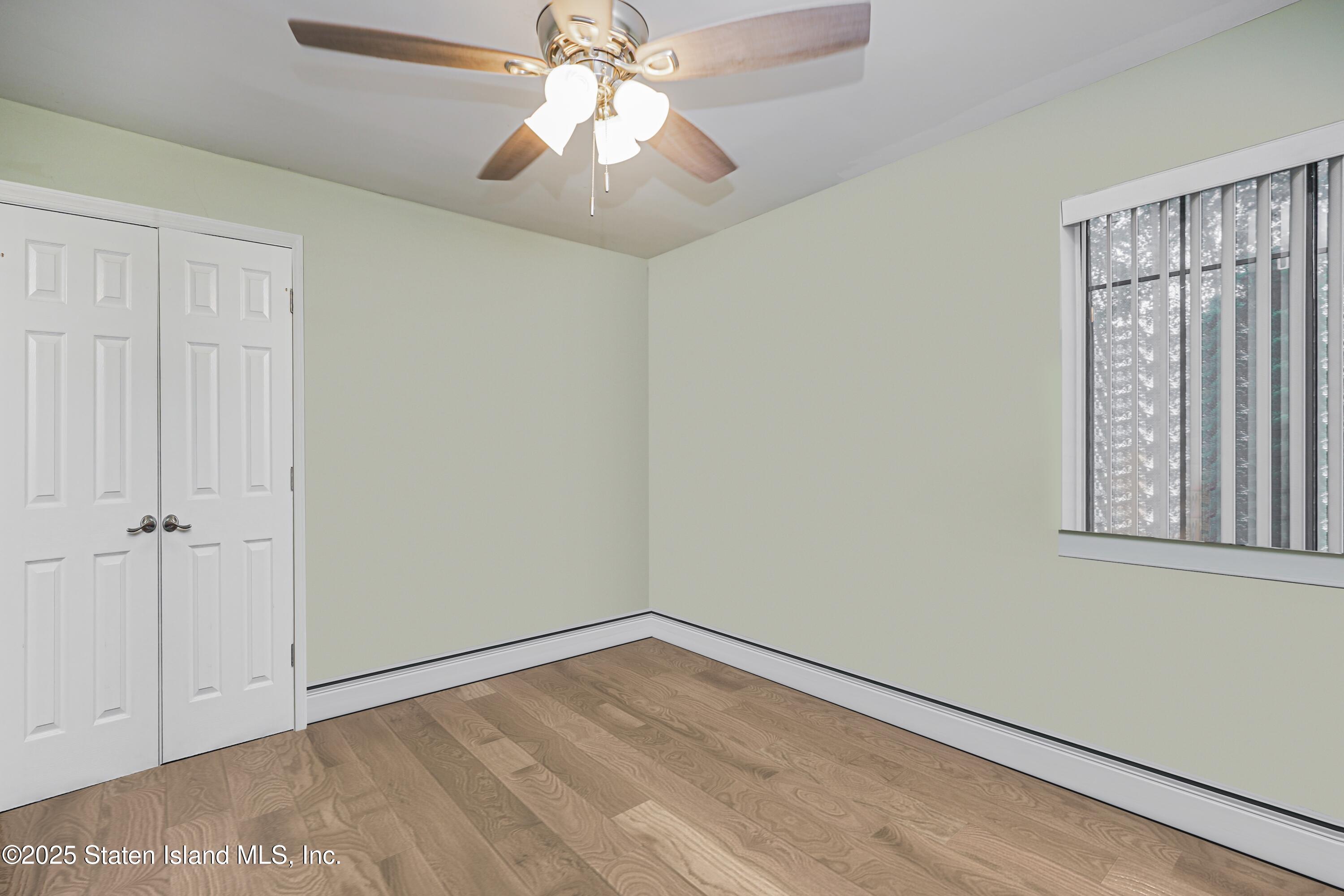 170 Devon Loop, Unit 3 Staten Island, NY 10314 - Photo 17 of 22 an empty room with wooden floor chandelier fan and windows