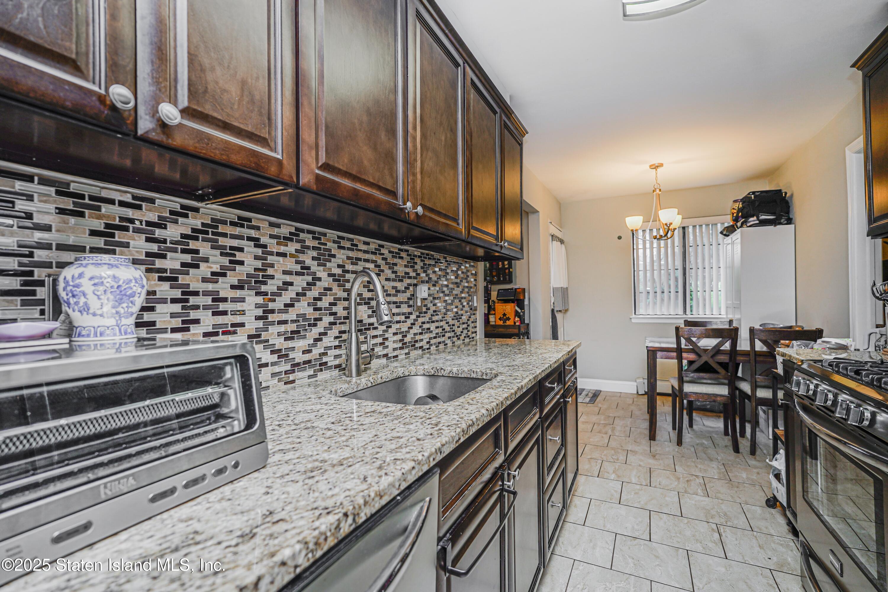 170 Devon Loop, Unit 3 Staten Island, NY 10314 - Photo 6 of 22 a kitchen with granite countertop a stove a sink and a microwave