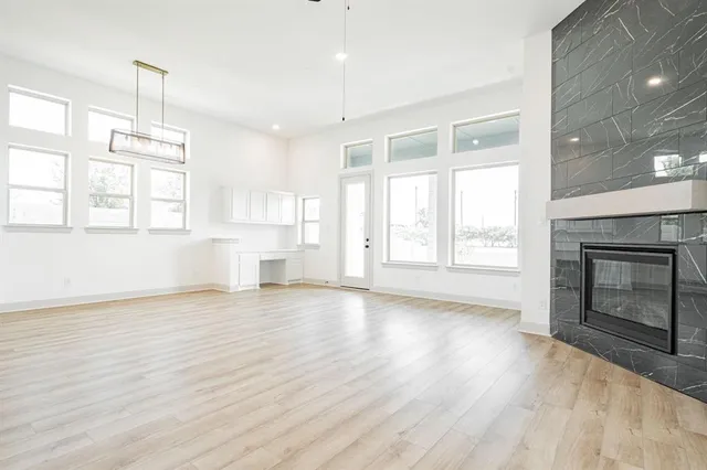 an empty room with wooden floor fireplace and windows