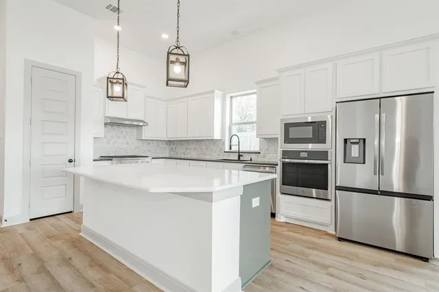 a kitchen with kitchen island white cabinets and stainless steel appliances