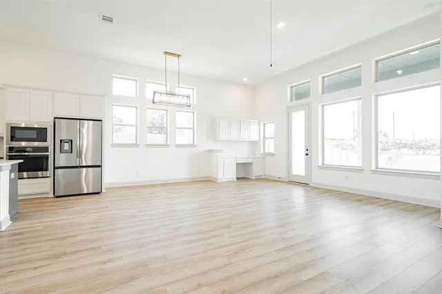 a view of a kitchen with wooden floor electronic appliances and windows