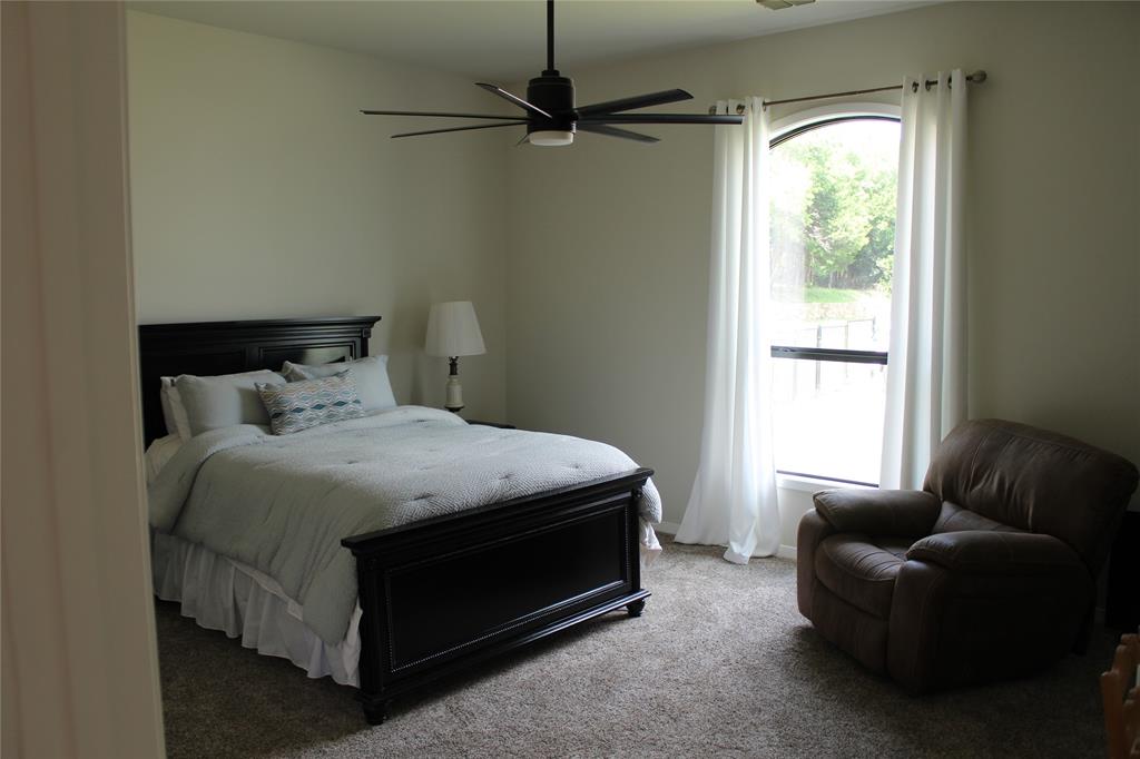 333 Renaissance Lane Heath, TX 75032 - Photo 20 of 35 Bedroom featuring a large arched window with white drapery rods, a modern ceiling fan with a light fixture, and textured carpet flooring