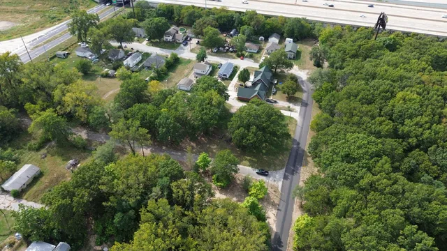 an aerial view of residential house with outdoor space and trees all around