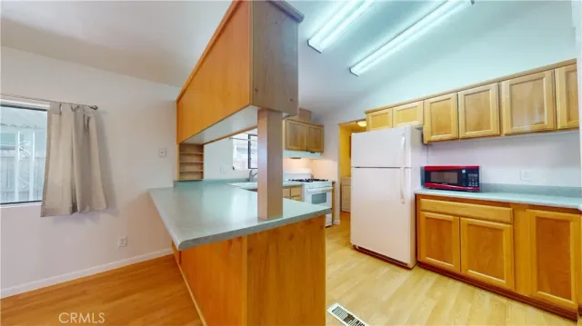 a view of a kitchen with fridge and wooden floor