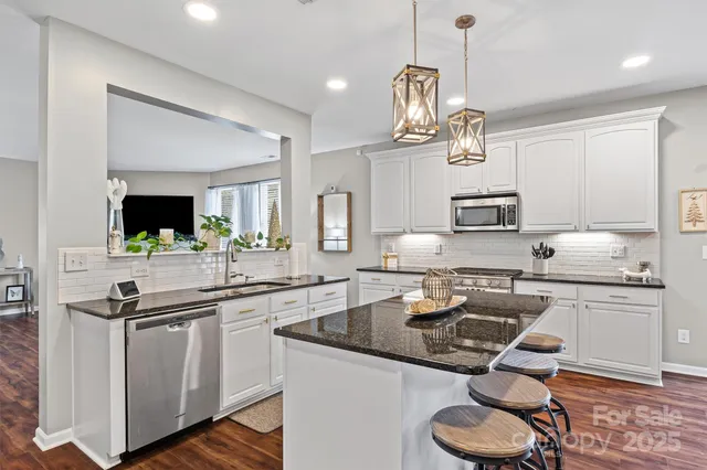 a kitchen with granite countertop a sink a stove and cabinets