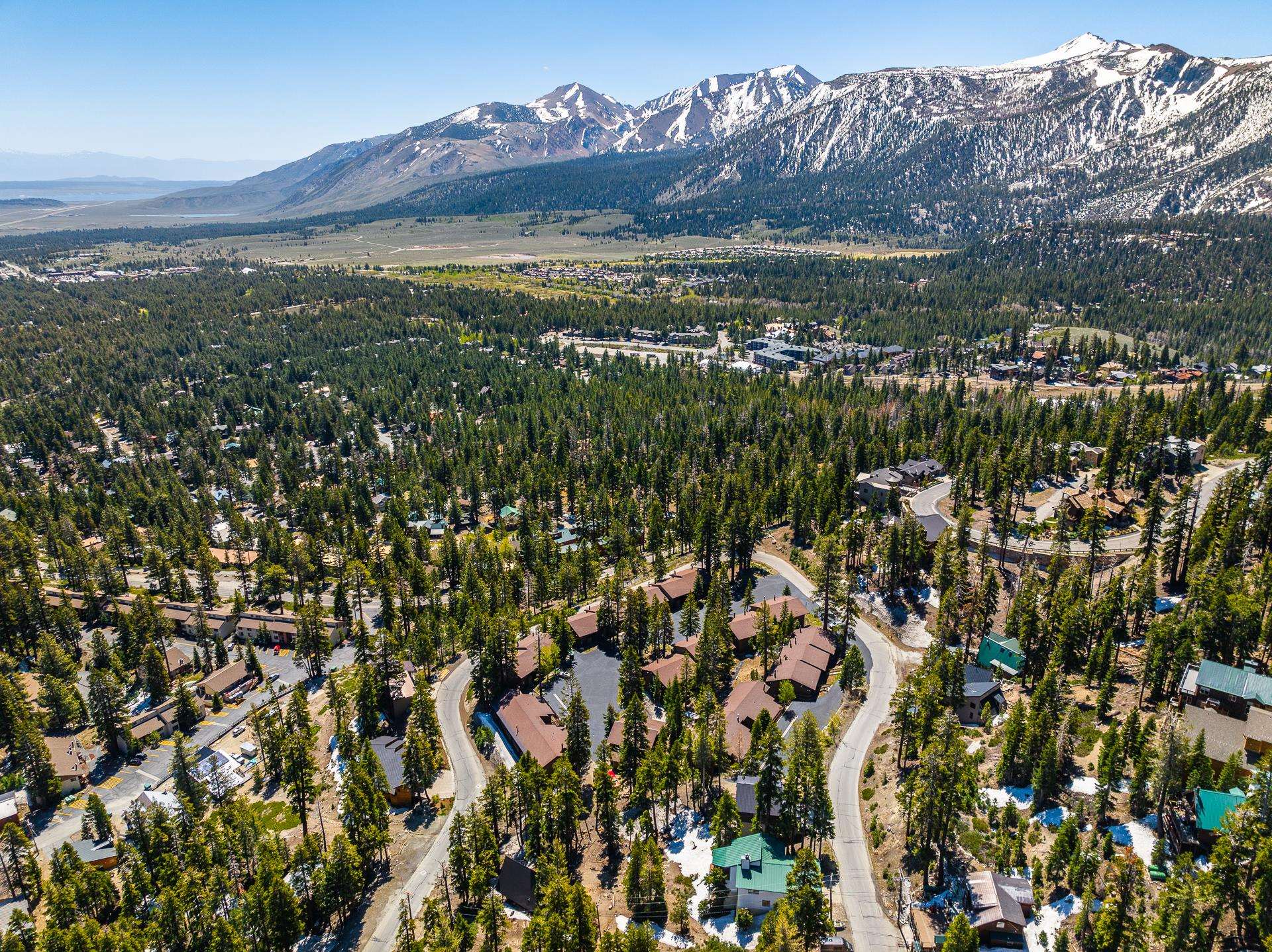94 John Muir Road, Unit 132 Mammoth Lakes, CA 93546 - Photo 49 of 58 Aerial perspective showcasing a community nestled among dense evergreen forests, with winding roads and distinct architectural styles