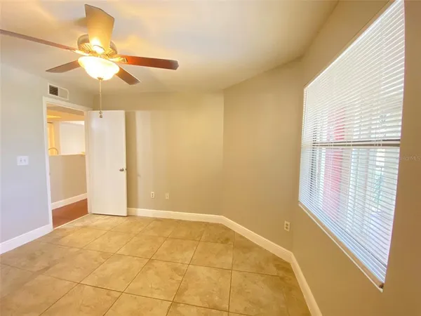 a view of an empty room with window and chandelier fan