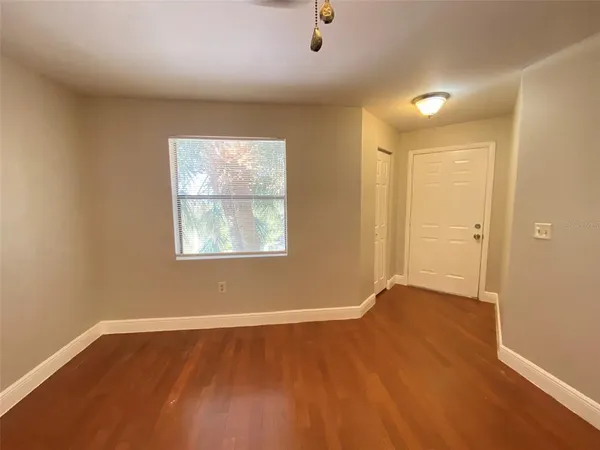 an empty room with wooden floor and windows