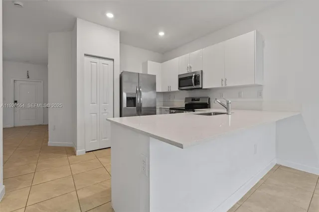 a kitchen with kitchen island white cabinets and stainless steel appliances