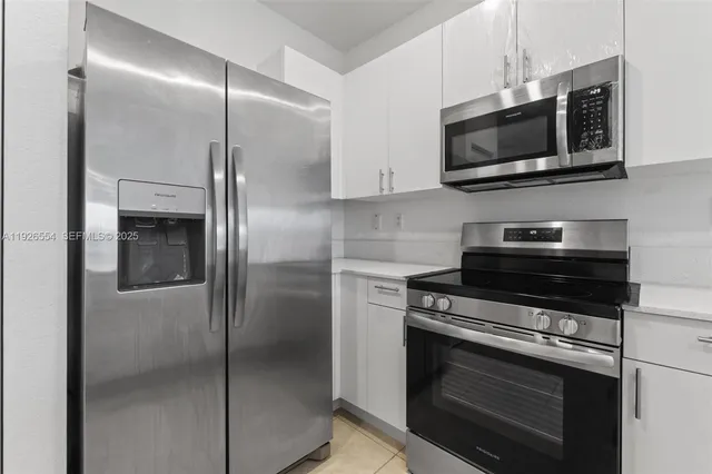 a kitchen with stainless steel appliances white cabinets and a stove top oven
