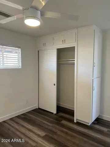 a view of an empty room with wooden floor and closet