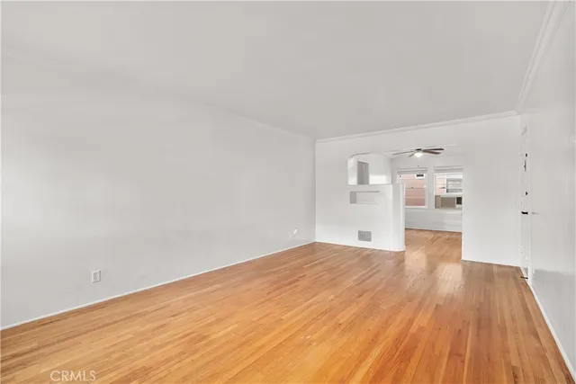 a view of a big room with wooden floor and windows