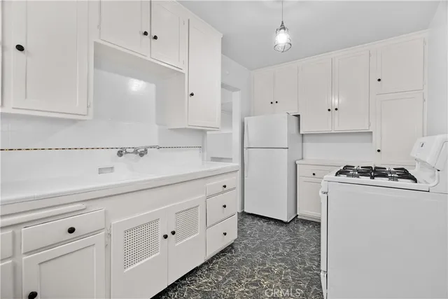 a kitchen with granite countertop white cabinets and refrigerator