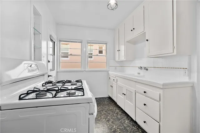 a kitchen with sink a stove and cabinets