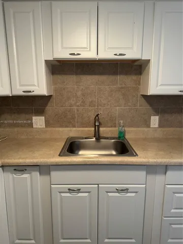 a kitchen with a sink stove and white cabinets