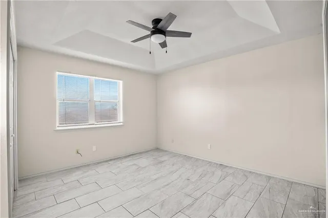 an empty room with chandelier fan and windows