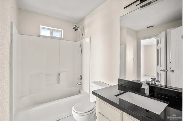 a bathroom with a granite countertop sink toilet a mirror and shower