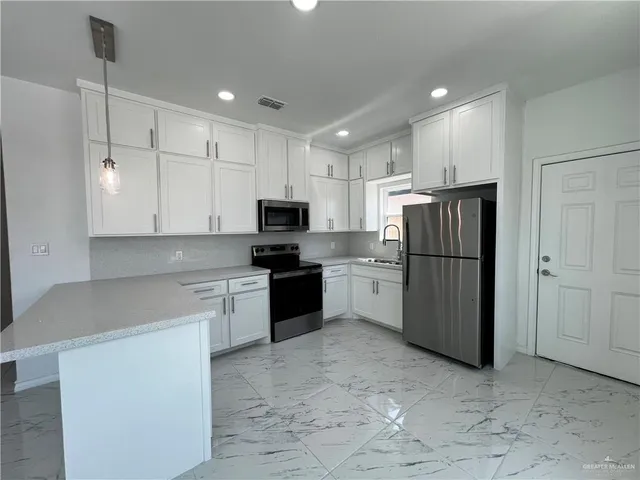 a kitchen with a refrigerator a stove top oven and white cabinets