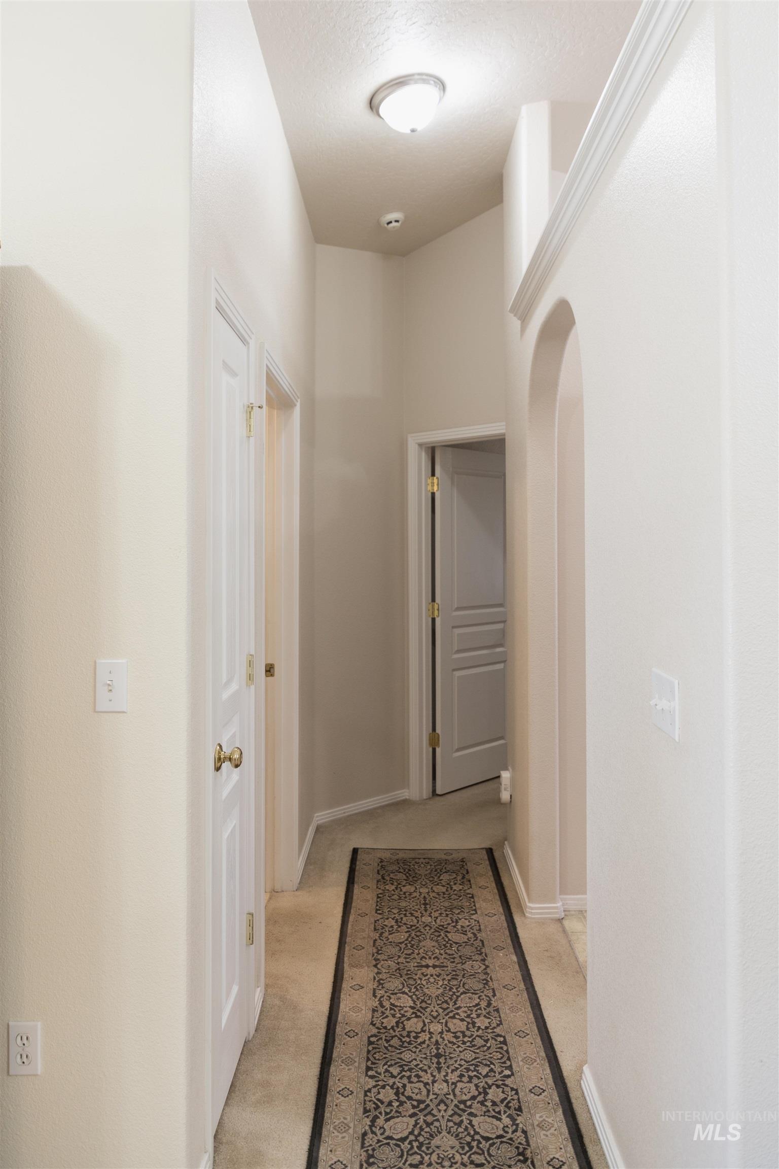 1003 Partridge Street Fruitland, ID 83619 - Photo 20 of 48 Hallway featuring light colored carpet, arched walkways, and a textured ceiling