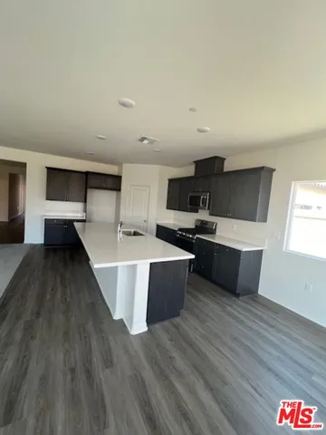 a large kitchen with stainless steel appliances a large counter top a stove and a wooden floors