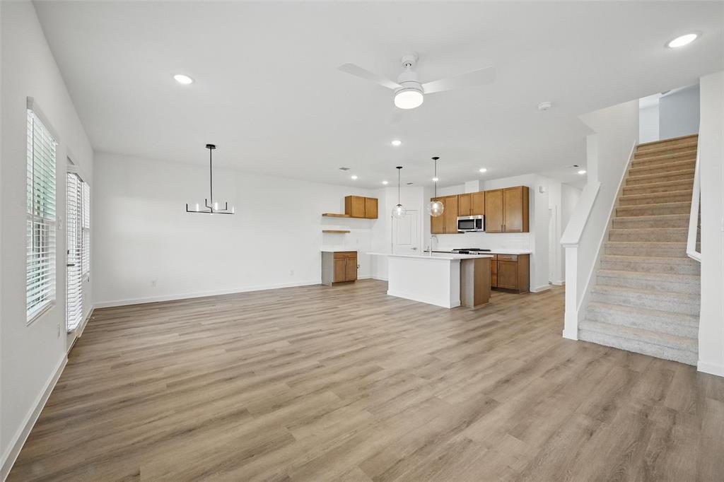 1413 Richardson Street Howe, TX 75459 - Photo 11 of 30 Open-concept living space featuring wood-finish flooring, a modern chandelier, and a ceiling fan