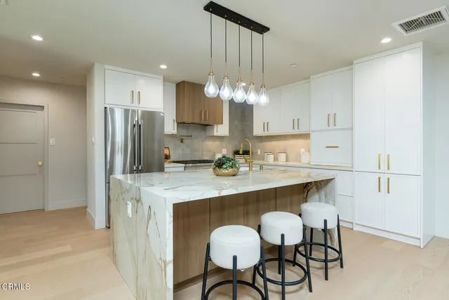 a kitchen with kitchen island a stove a chandelier a refrigerator and chairs