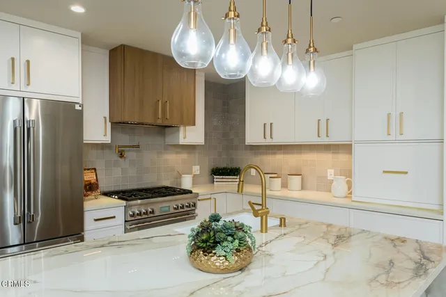 a kitchen with stainless steel appliances granite countertop a sink a stove and a refrigerator