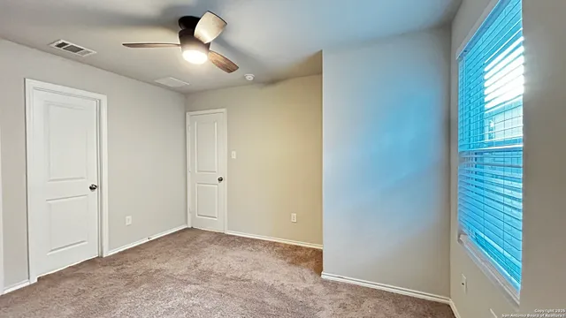 a view of an empty room and window and ceiling fan